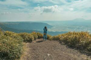 The woman standing on the top of mountain with green lanscape with mountain Aso background, Daikanbo Mount Aso, Aso, Kumamoto, Kyushu, Japan, vintage style photo