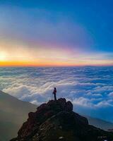 Silhouette on Mountain Summit at Sunrise Silhouette standing on rocky summit, observing tranquil sea and beautiful landscape. photo