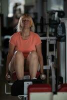A middle aged woman in a gym on one of the training machines photo
