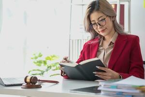 A knowledgeable and confident female lawyer working in an office with law books sitting at the table. Learn, and study, legal services, advice, justice, and real estate concepts. photo