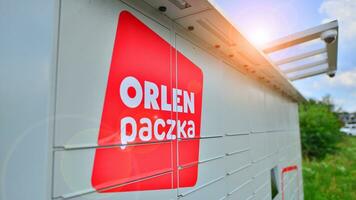 Warsaw, Poland. 6 August 2023. Package collection machine, delivery service. Smart electronic steel parcel locker box, automatic mailboxes. Orlen Paczka parcel machine with logo sign. photo