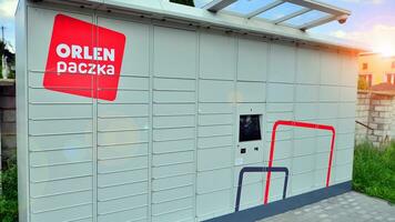 Warsaw, Poland. 6 August 2023. Package collection machine, delivery service. Smart electronic steel parcel locker box, automatic mailboxes. Orlen Paczka parcel machine with logo sign. photo