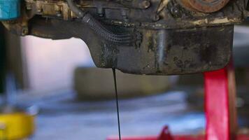 antiguo petróleo drenando desde el sumidero enchufe de el coche motor en el reparar tienda imágenes. video