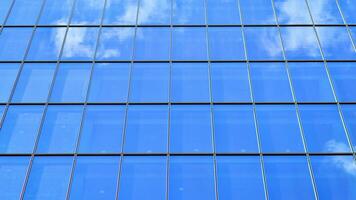 Structural glass wall reflecting blue sky. Abstract modern architecture fragment. Glass building with transparent facade of the building and blue sky. Contemporary architectural background. photo