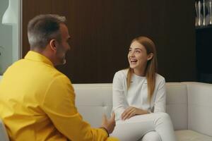 A dentist in a white coat talks about the teeth to a girl in a yellow dress who lies on the couch photo