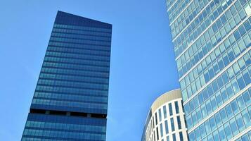Modern office building with glass facade on a clear sky background. Transparent glass wall of office building. photo