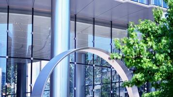Eco architecture. Details of facade glass and aluminum panels on  building. Green tree and modern office building. The harmony of nature and modernity. photo