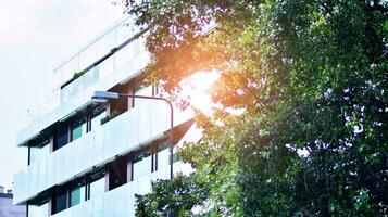 Modern residential building with new apartments in a green residential area. Eco architecture. Green tree and new apartment building. The harmony of nature and modernity. photo