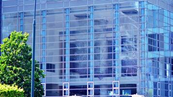 Eco architecture. Details of facade glass and aluminum panels on  building. Green tree and modern office building. The harmony of nature and modernity. photo