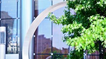 Eco architecture. Details of facade glass and aluminum panels on  building. Green tree and modern office building. The harmony of nature and modernity. photo