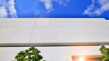 Modern white concrete building walls against blue sky. Eco architecture. Green trees and concrete office building. The harmony of nature and modernity. photo