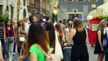 Warsaw, Poland. 29 July 2023. Crowd of people walking on a street. A crowd moving against a background of an urban old city landscape. photo