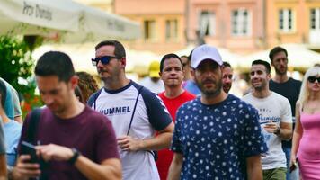 varsovia, Polonia. 29 julio 2023. multitud de personas caminando en un calle. un multitud Moviente en contra un antecedentes de un urbano antiguo ciudad paisaje. foto