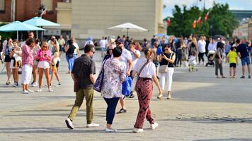 Warsaw, Poland. 29 July 2023. Crowd of people walking on a street. A crowd moving against a background of an urban old city landscape. photo