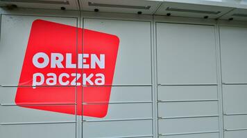 Warsaw, Poland. 6 August 2023. Package collection machine, delivery service. Smart electronic steel parcel locker box, automatic mailboxes. Orlen Paczka parcel machine with logo sign. photo