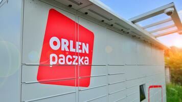 Warsaw, Poland. 6 August 2023. Package collection machine, delivery service. Smart electronic steel parcel locker box, automatic mailboxes. Orlen Paczka parcel machine with logo sign. photo