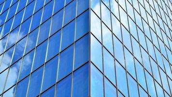 Structural glass wall reflecting blue sky. Abstract modern architecture fragment. Glass building with transparent facade of the building and blue sky. Contemporary architectural background. photo