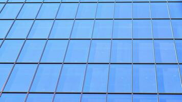 Structural glass wall reflecting blue sky. Abstract modern architecture fragment. Glass building with transparent facade of the building and blue sky. Contemporary architectural background. photo