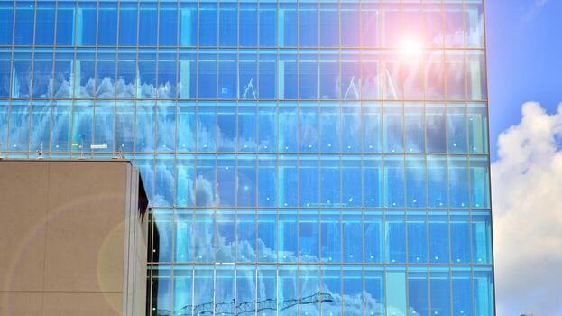 Glass modern building with blue sky background. View and architecture details. Urban abstract - windows of glass office building in  sunlight day. photo