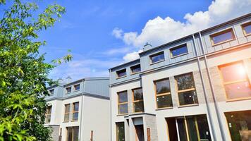 New single family houses in a new development area. Residential homes with modern facade. Terraced family homes in newly developed housing estate. The real estate market in the suburbs. photo