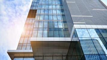 Abstract fragment of contemporary architecture, walls made of glass and concrete. Abstract closeup of the glass-clad facade of a modern building covered in reflective plate glass. photo