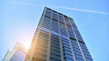 Modern office building with glass facade on a clear sky background. Transparent glass wall of office building. photo