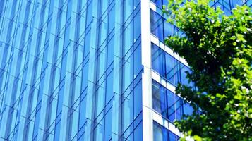 Eco architecture. Details of facade glass and aluminum panels on  building. Green tree and modern office building. The harmony of nature and modernity. photo