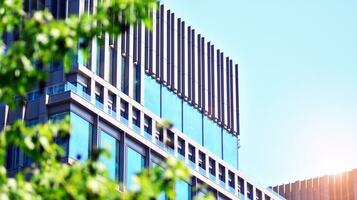 Eco architecture. Details of facade glass and aluminum panels on  building. Green tree and modern office building. The harmony of nature and modernity. photo