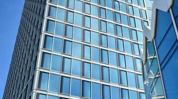 Abstract fragment of contemporary architecture, walls made of glass and concrete. Abstract closeup of the glass-clad facade of a modern building covered in reflective plate glass. photo