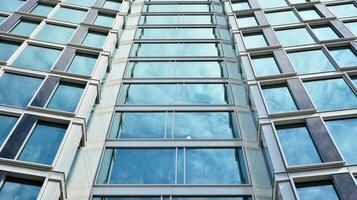 Abstract fragment of contemporary architecture, walls made of glass and concrete. Abstract closeup of the glass-clad facade of a modern building covered in reflective plate glass. photo