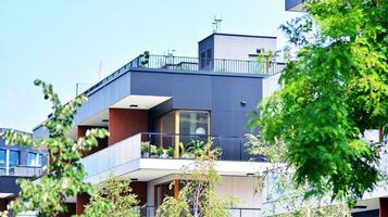 Modern residential building with new apartments in a green residential area. Eco architecture. Green tree and new apartment building. The harmony of nature and modernity. photo