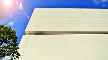 Modern white concrete building walls against blue sky. Eco architecture. Green trees and concrete office building. The harmony of nature and modernity. photo