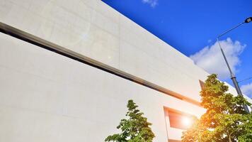 Modern white concrete building walls against blue sky. Eco architecture. Green trees and concrete office building. The harmony of nature and modernity. photo