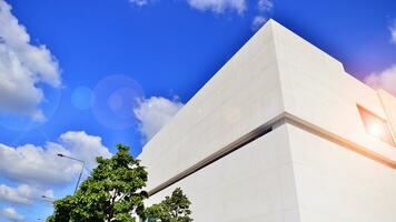 Modern white concrete building walls against blue sky. Eco architecture. Green trees and concrete office building. The harmony of nature and modernity. photo