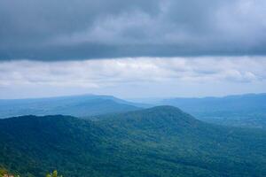 Big green mountains and lots of trees in the mountains. clouds floating on the mountain photo