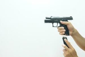 One hand holding the gun pointing forward and the other inserting the mag into the gun on a white background. photo