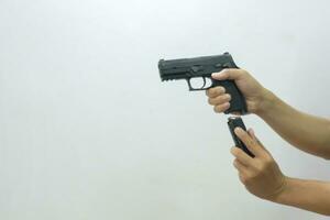 One hand holding the gun pointing forward and the other inserting the mag into the gun on a white background. photo