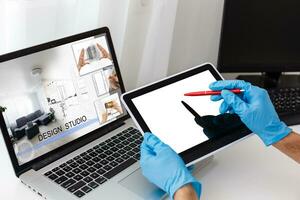 Man in medical mask and rubber gloves sits at home on a table and works with laptop during quarantine. Designer, artist, architect, businessman at remote work in a pandemic covid. Coronavirus. photo