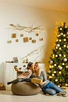 Mother and daughter sitting by a fireplace in their cozy family home enjoying winter evening photo