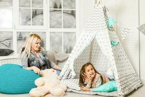 Woman wearing cute animal house slippers sitting on the floor in handmade wigwam photo