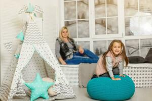 Smiling mother and child daughter in the nursery, happy time and togetherness photo