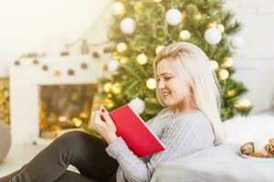 contento mujer con libro cerca Navidad árbol foto