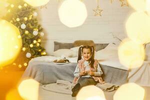 pequeño niña mentiras en un cama en un habitación decorado para Navidad foto