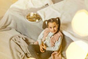 pequeño niña se sienta en un habitación decorado para Navidad foto