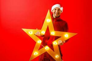 Photo of cheerful man in Santa's cap with Christmas star garland in hands