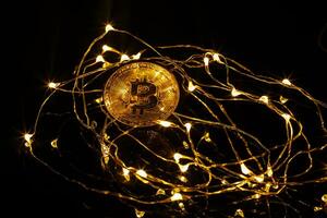 dorado bitcoin y otro bitcoin en espalda con Navidad decoraciones y luces foto