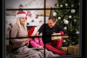 alegre Navidad y contento Días festivos ventana . familia preparación cerca el Navidad árbol a hogar foto