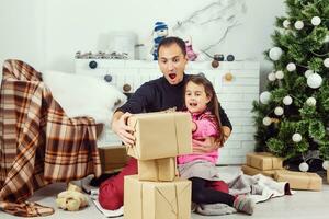 Portrait of a surprised little girl with her father holding a Christmas present photo