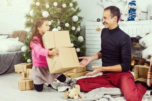 alegre Navidad y contento vacaciones. familia preparación cerca el Navidad árbol a hogar foto