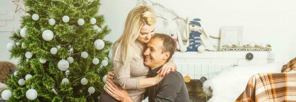 Nice love couple sitting on carpet in front of fireplace. Woman and man celebrating Christmas photo